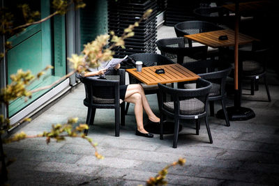 Woman reading newspaper while sitting on chair in cafe