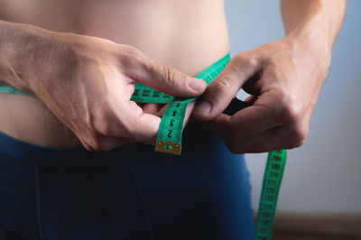 Cropped hand of man holding tape measure