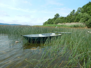 Deck chairs in lake against sky