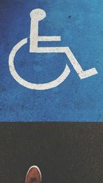 Low section of man by wheelchair sign on road