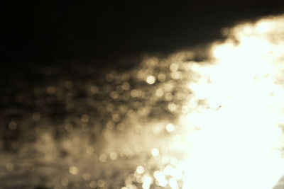 Defocused image of illuminated lights against sky at night