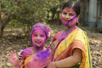 Indian mother and daughter in colorful faces during holi