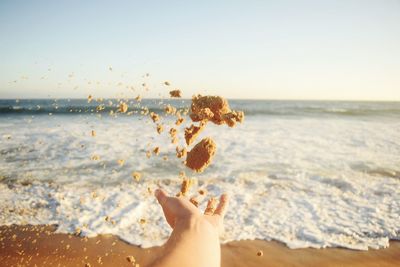 Cropped hand throwing sands at beach