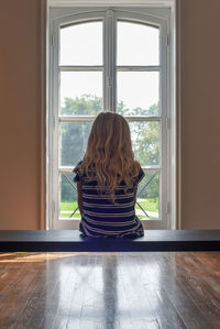 Rear view of woman sitting on wood over floor at home