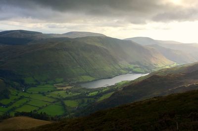 Scenic view of landscape mountains  and a lake against moody misty sky 