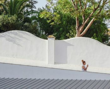 Full length of woman with arms raised on roof against sky