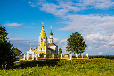 Beautiful christian church with golden domes among green trees.