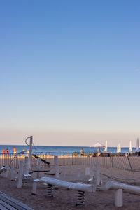 Pier on beach against clear blue sky