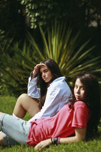 Friends resting on field against trees