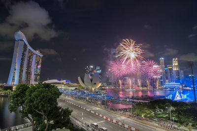 Firework display in city against sky at night