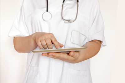 Midsection of doctor using digital tablet against white background