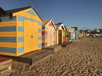 Beach huts by buildings against clear sky