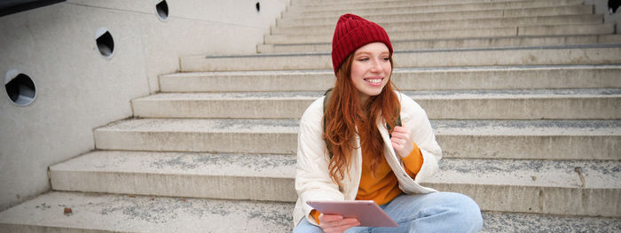 Portrait of young woman standing against steps