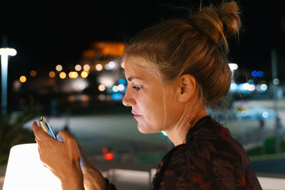 Portrait of young woman using smart phone at night