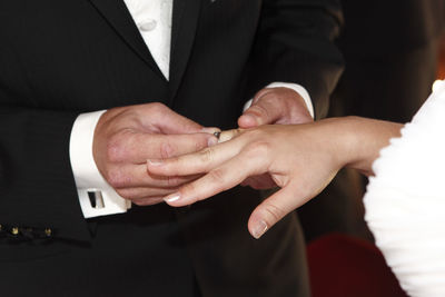 Midsection of bridegroom holding hands