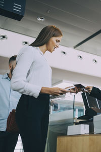 Low angle view of smiling young businesswoman checking in at airport