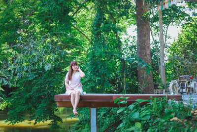 Side view of woman sitting in forest