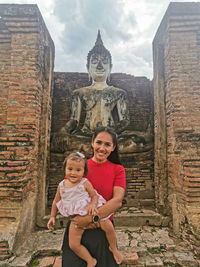 Portrait of smiling woman with baby against temple