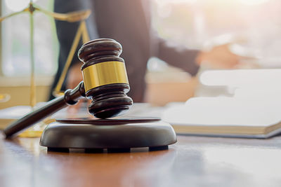 Midsection of judge working at desk with gavel and weight scale