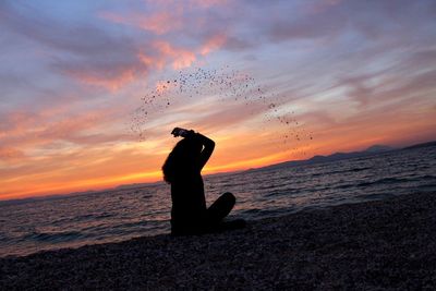 Silhouette of man in sea against sunset sky