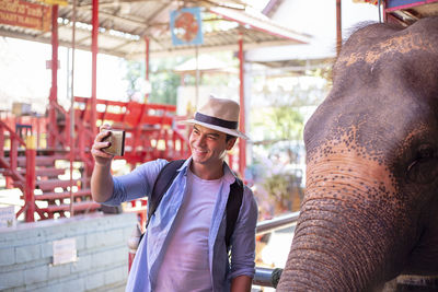 Man taking selfie while standing by elephant