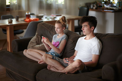 Siblings playing video game on couch at home