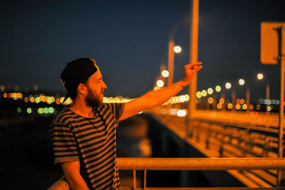 Young man gesturing on bridge at night