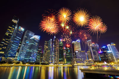 Firework display over illuminated buildings in city at night