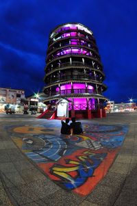 Graffiti on illuminated city street against sky at dusk