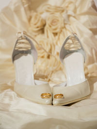 Close-up of wedding rings on high heels and dress