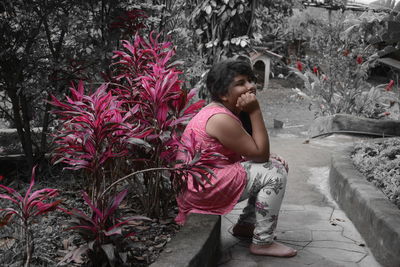 Woman sitting on plant against trees