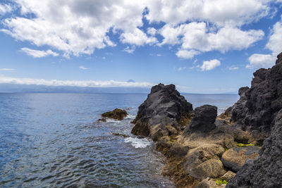 Rocks on sea shore against sky