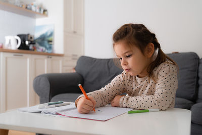 Portrait of cute preschooler child girl drawing with pencils at home 
