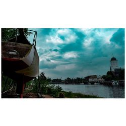 Buildings by river against sky