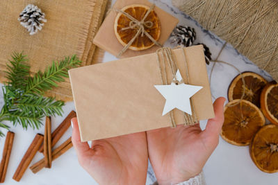 Cropped hand of woman holding gift on table