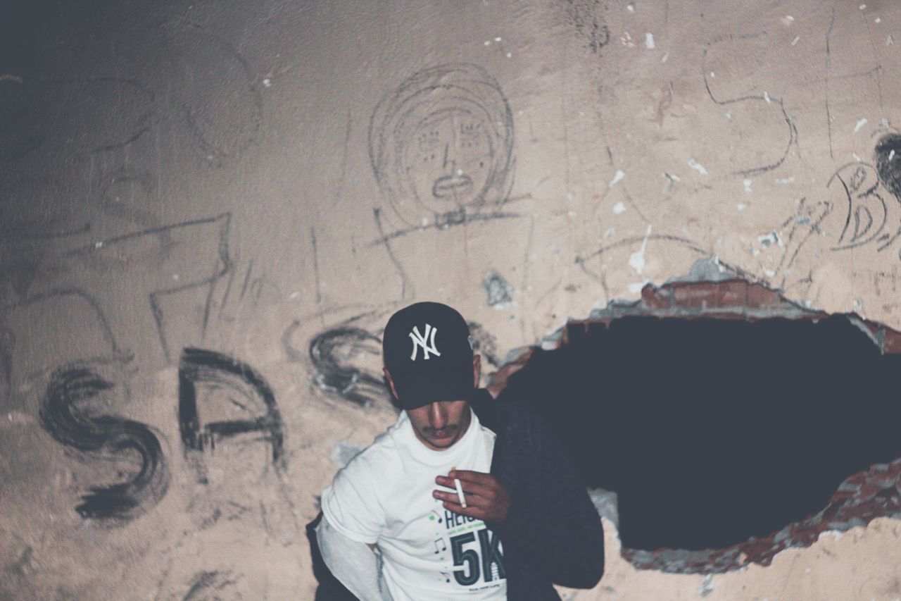 real people, graffiti, one person, lifestyles, wall - building feature, architecture, text, leisure activity, standing, built structure, men, day, street, high angle view, creativity, communication, city, outdoors, wall