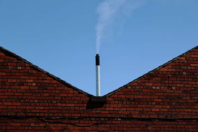 Low angle view of factory against blue sky