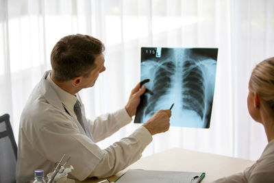 Doctor showing medical x-ray to patient at clinic