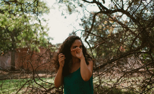 Portrait of young woman standing against trees