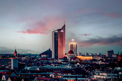 Modern buildings in city against sky during sunset