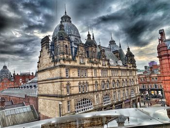 View of buildings in city against cloudy sky