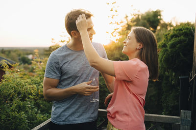 Smiling couple talking while standing at balcony in yard