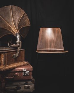 Wooden chair with gramophone and suitcase on black background