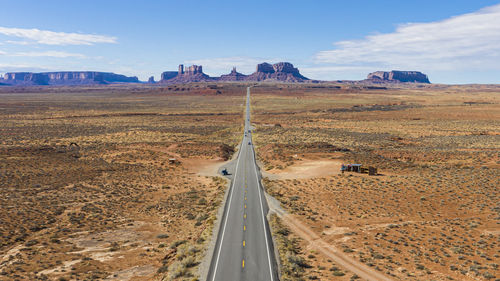 Empty road amidst landscape against sky