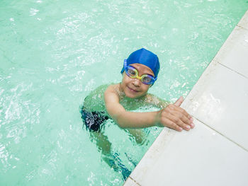 High angle view of smiling boy swimming in pool