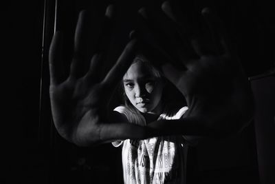 Portrait of woman standing against black background