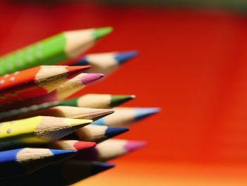 Close-up of multi colored pencils against red background