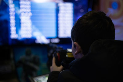 Rear low light view of kid playing in a virtual game machine.