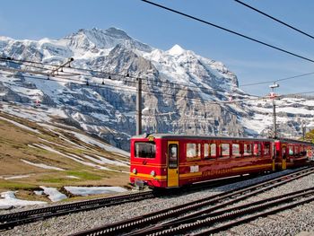 Train on railroad track by snowcapped mountains against sky