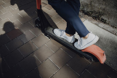 Businessman with e-scooter in the city, low section